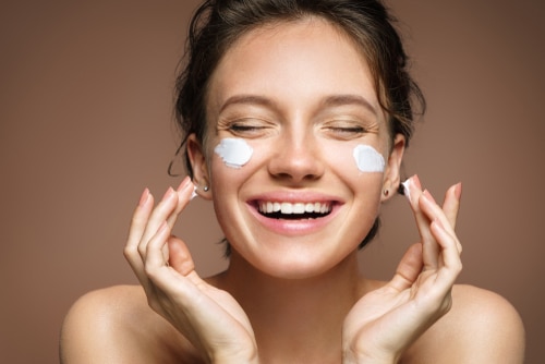 laughing girl applying moisturizing cream on her face-img-blog