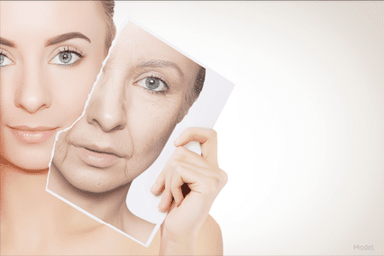 Young woman holding a photo of her aged self.