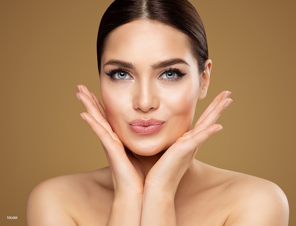Young woman touching her face with her hands